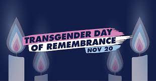 Navy blue background with four white candles, each displaying pale blue, pink and white flames. A banner across the candles reads: Transgender Day of Remembrance